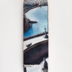Fotografía de un skate con vistas a una isla distante, combinando el ambiente urbano del skate con un tranquilo paisaje marítimo.